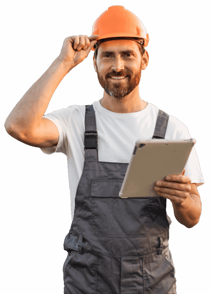 A man in work overalls and an orange safety helmet holding a tablet.