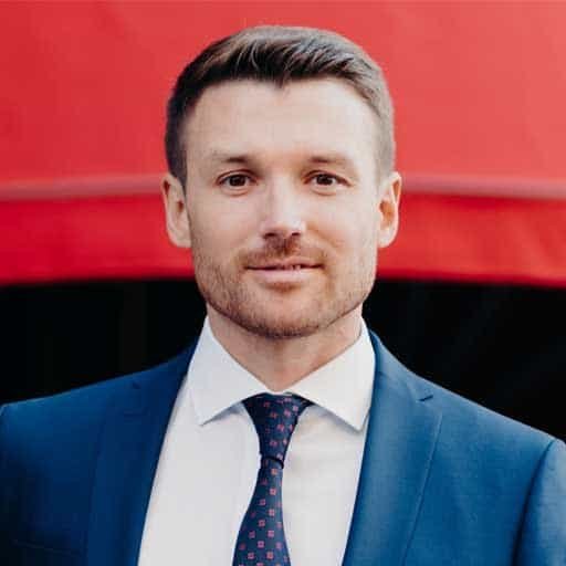 Expert roofing professional in a suit, standing outdoors with a red background.